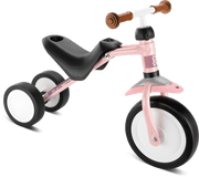 PUKY PUKYMOTO är en rosa och svart trehjuling med ett stort framhjul, två små bakhjul, en svart sits och bruna handtag på styret, mot en vit bakgrund.