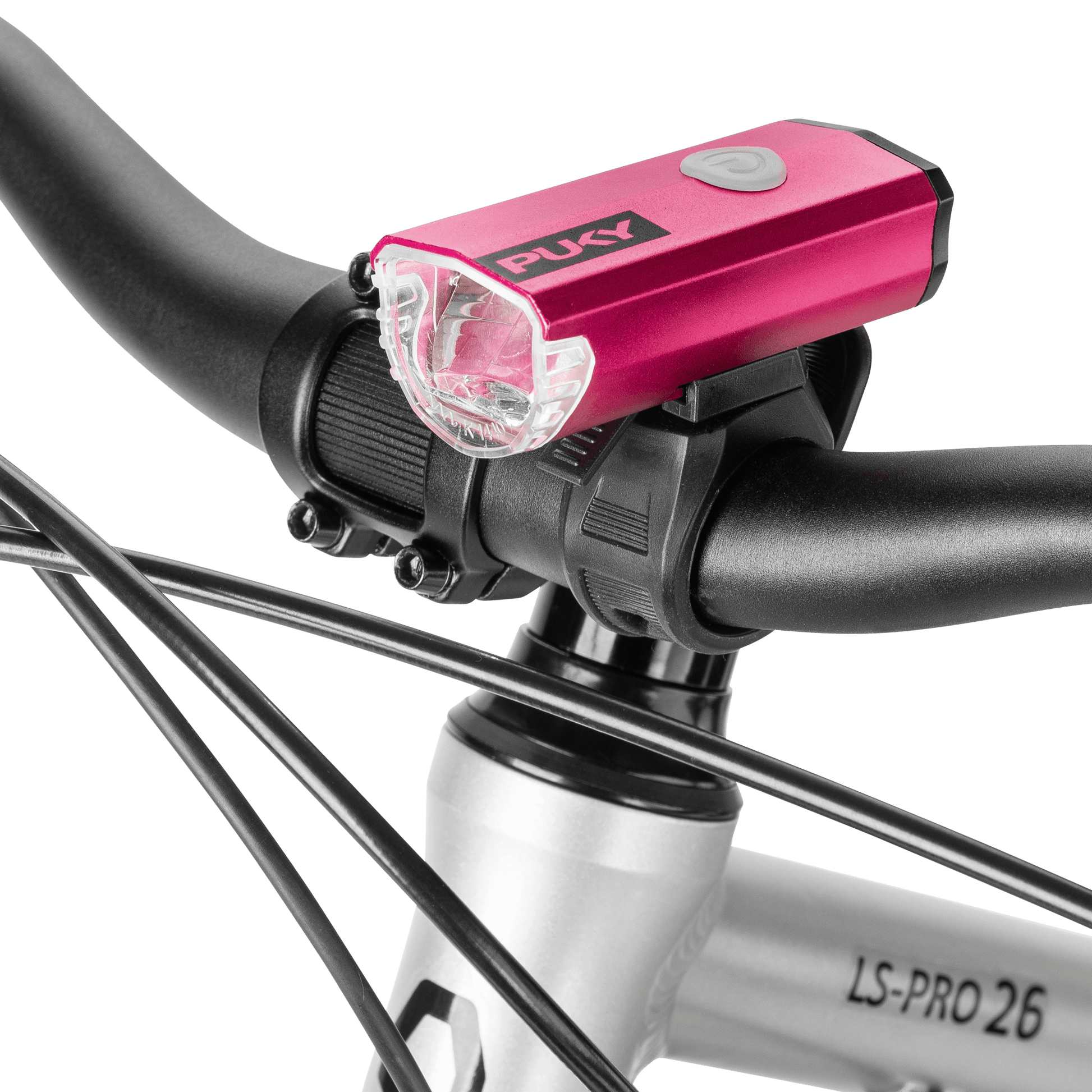 Närbild av en rosa PUKY LUMI cykellampa monterad på styret på en silverfärgad cykel märkt "LS-PRO 26", med synliga svarta kablar.