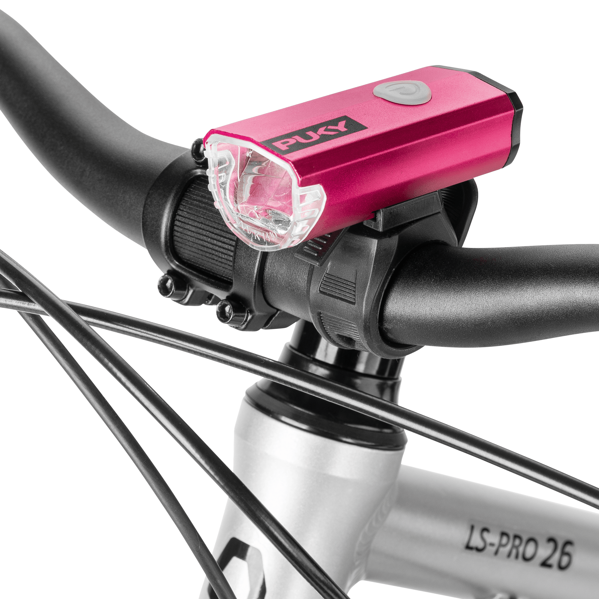 Närbild av en rosa PUKY LUMI cykellampa monterad på styret på en silverfärgad cykel märkt "LS-PRO 26", med synliga svarta kablar.