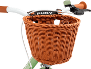 Närbild av ett ljusgrönt cykelstyre med bruna handtag och en korg CHAOS KORB - L framtill, som hålls fast med bruna läderremmar. Varumärket PUKY syns på ramen bakom korgen.